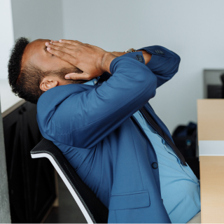 Un homme visiblement stressé et accablé, tenant sa tête dans ses mains, illustrant les effets du stress et des risques psychosociaux au travail.